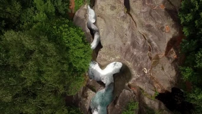 空中无人机拍摄了郁郁葱葱的山谷和河流中的陡峭瀑布