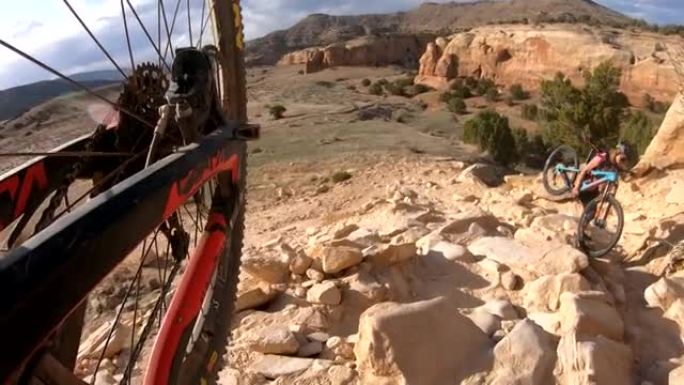 女性山地自行车手在沙漠中骑着自行车爬上陡峭的岩石