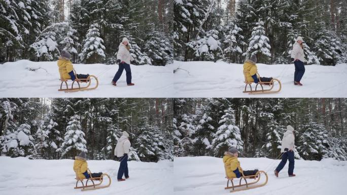 快乐的女人和她的小儿子在森林里玩得开心，母亲带着孩子拉雪橇