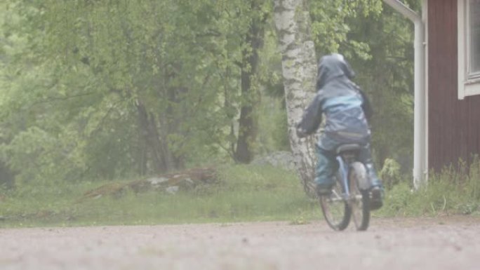 极端天气-一个年幼的孩子在大雨中骑自行车