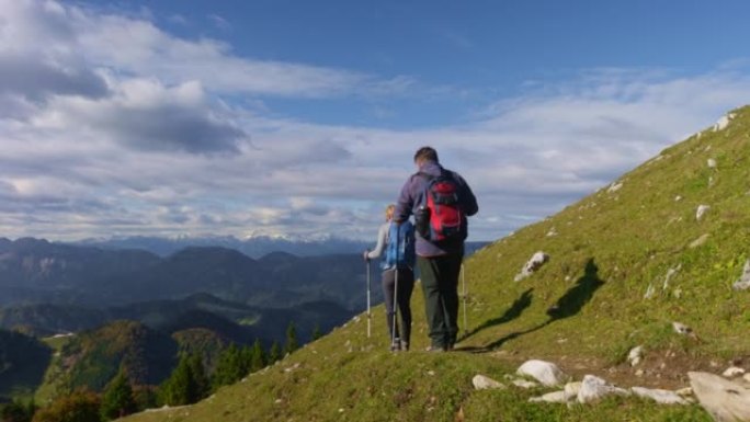 一个高级男人和一个女人在阳光下的风景优美的小径上下山