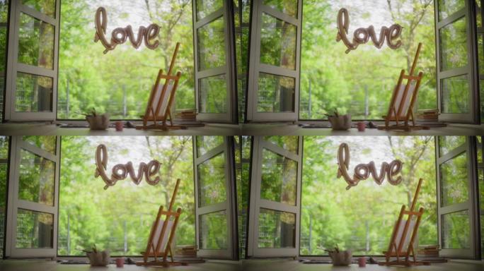 绿色背景上的 “爱” 排版气球。夏日打开窗户，画架和窗台上的油漆