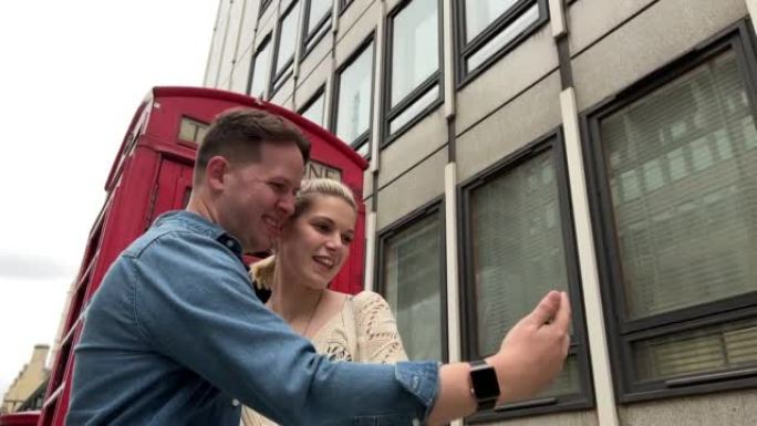 可爱的高加索夫妇在英国伦敦旅游时，在一个标志性的旅游红色电话亭一起自拍