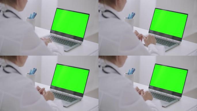 女医师正在寻找用于色度关键技术的笔记本电脑的绿色显示，通过视频聊天或视频通话在线交流