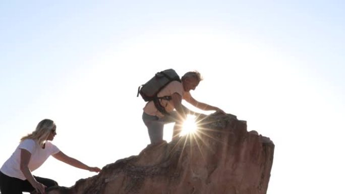 徒步旅行夫妇登上沙漠景观上方的岩岭