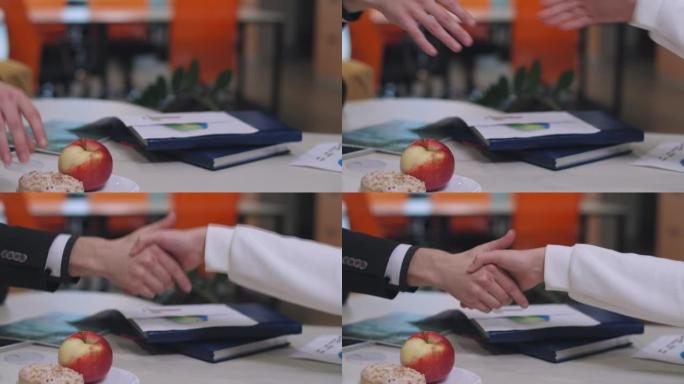 室内午休时无法辨认的高加索男人和女人的特写握手。自信成功的商业伙伴在咖啡馆共进晚餐。合作与伙伴关系。