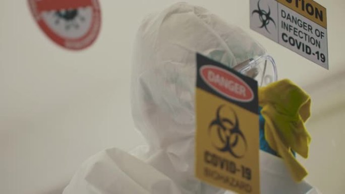 新型冠状病毒肺炎: 亚洲男子穿着防护服，手套和消毒湿巾