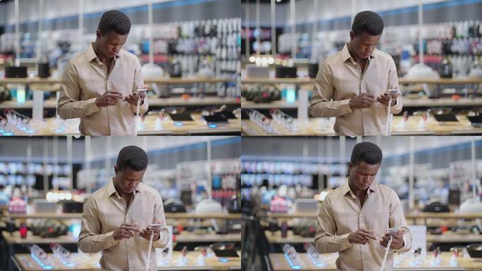 严肃的非裔美国人正在数字设备商店查看智能手机，在购买前测试新型号