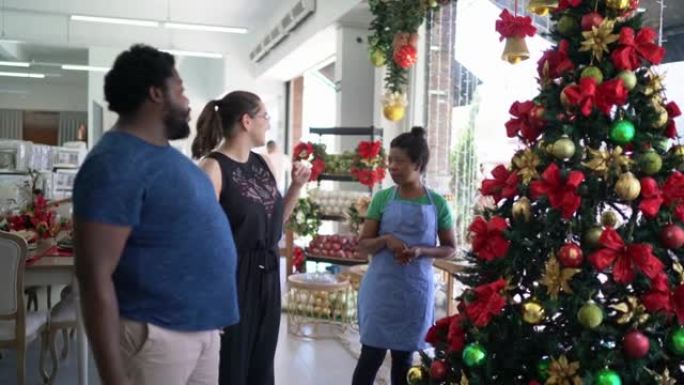 女售货员帮助一对夫妇在装饰店购买圣诞树