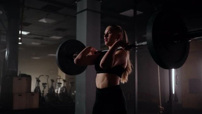 强壮的女性运动员，肌肉发达的身体举重，用杠铃锻炼。女性在健身房用哑铃做运动
