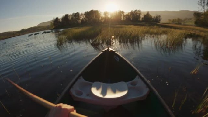 户外冒险: 日落时POV在湖中划独木舟