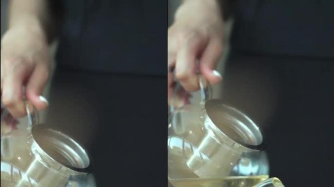 女性手捧壶将茶倒入杯子的特写镜头