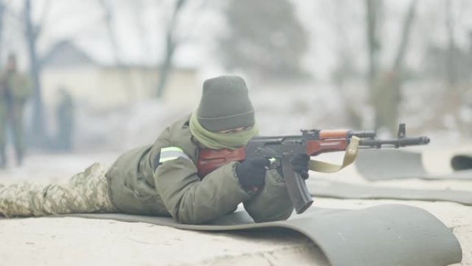 严肃自信的女兵躺在多边形上，用步枪慢动作射击。职业白人女军人在户外训练的肖像。