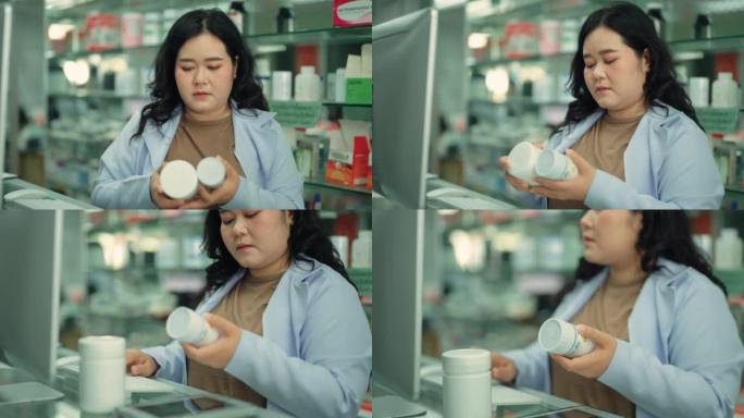 亚洲女药剂师在药房柜台使用电脑时持药