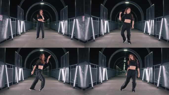 美丽的年轻女子在地铁穿越的黑暗隧道中跳舞富有表现力的嘻哈舞蹈
