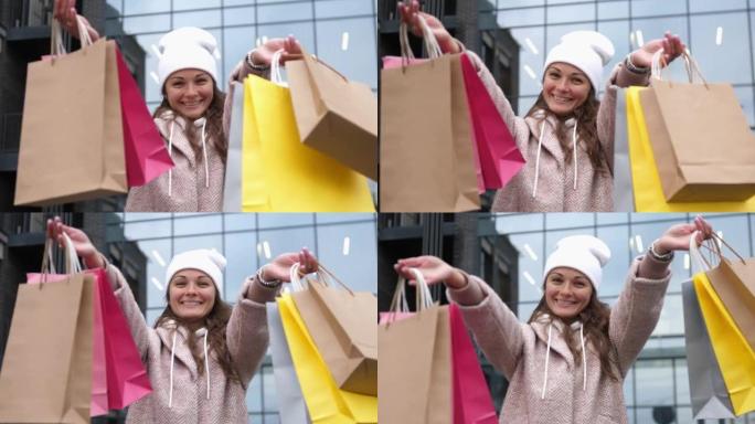 快乐的女孩拿着五颜六色的购物袋，在街上向相机展示
