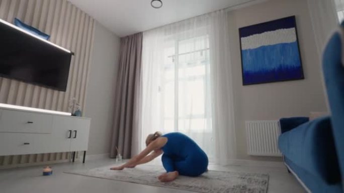 一个运动的美女在家里用头和手表演站立。在他自己公寓的地毯上。平衡练习