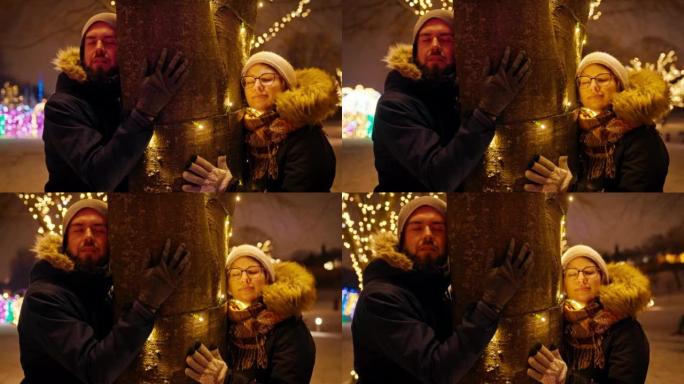 一对夫妇在下雪的夜晚以慢动作拥抱圣诞树