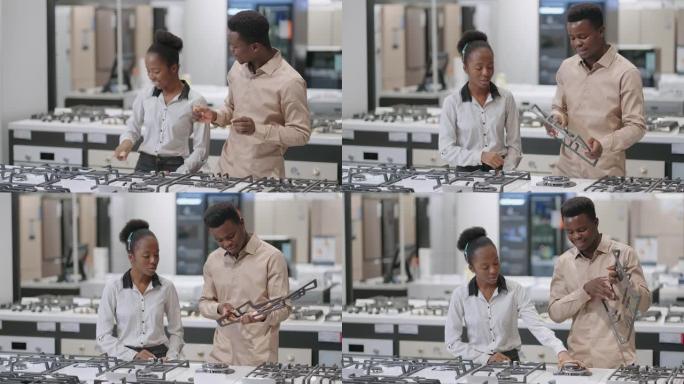 幸福的新婚夫妇正在为厨房购买新设备，美国黑人夫妇正在购物中心的家电商店中选择燃气灶，配偶正在查看烹饪
