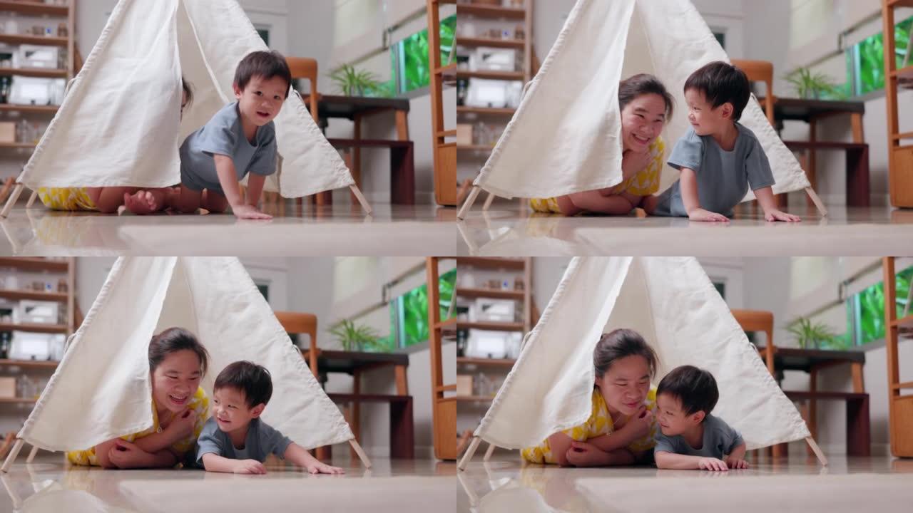 快乐的孩子男孩在家里的帐篷里和妈妈玩躲猫猫