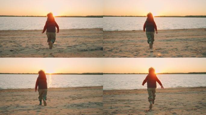 快乐的卷曲小男孩在日落时分在桑迪河海岸上空奔跑，慢动作，后视图，随后拍摄