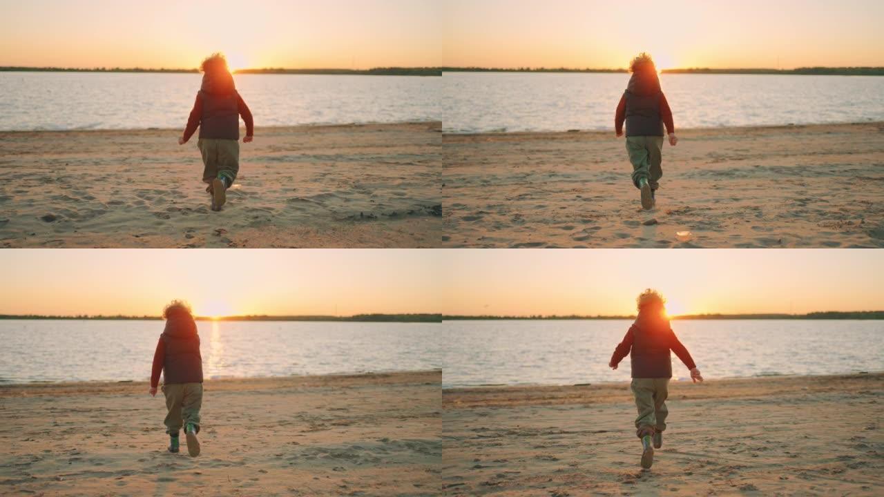 快乐的卷曲小男孩在日落时分在桑迪河海岸上空奔跑，慢动作，后视图，随后拍摄