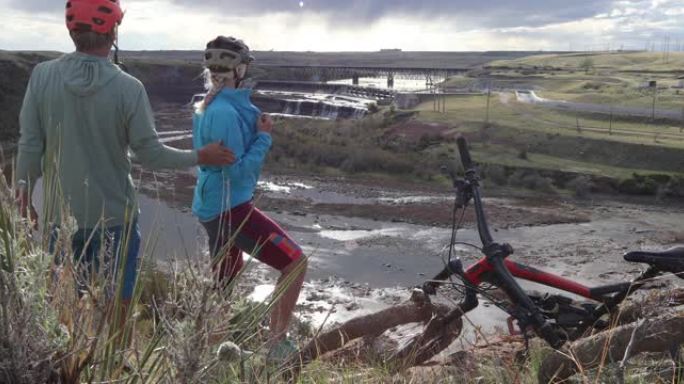 山地自行车夫妇在密苏里河和水力发电大坝上方停顿