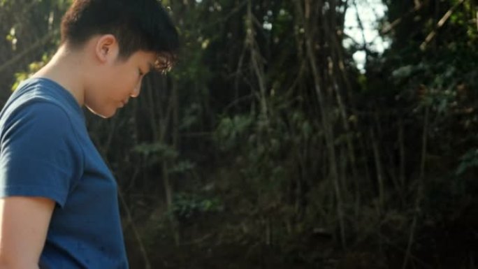 快乐的亚洲男孩在丛林中的河里放松阳光，户外生活方式的概念。