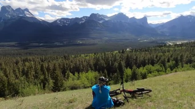 女性山地自行车手在高山草甸放松，骑自行车
