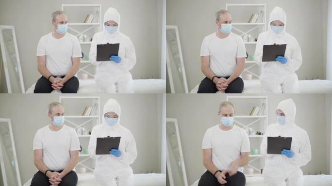 医生在抗病毒服填写文件，病人在面罩咳嗽。中年男子在新型冠状病毒肺炎大流行禁闭中拜访医生的肖像。冠状病