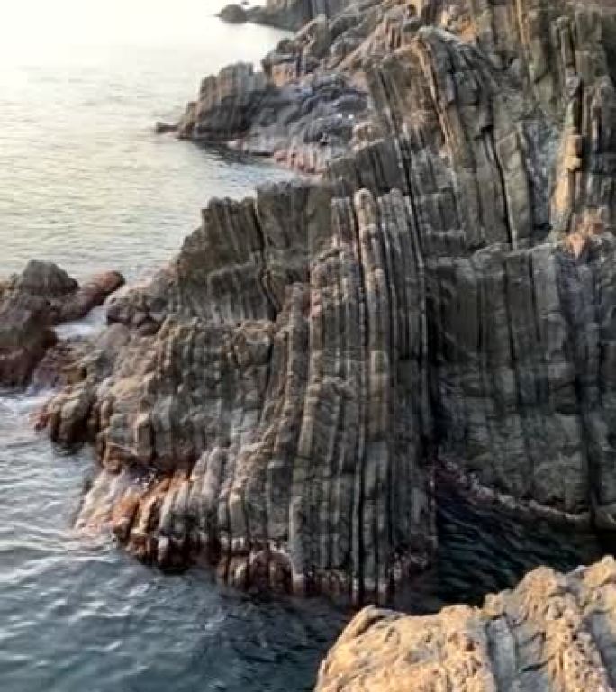 岩石海岸线向日落平移的垂直镜头