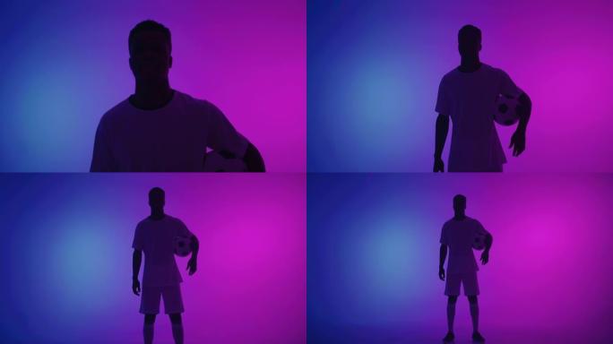 非裔美式足球运动员在工作室里带球，带蓝色和紫色的灯光，剪影射击