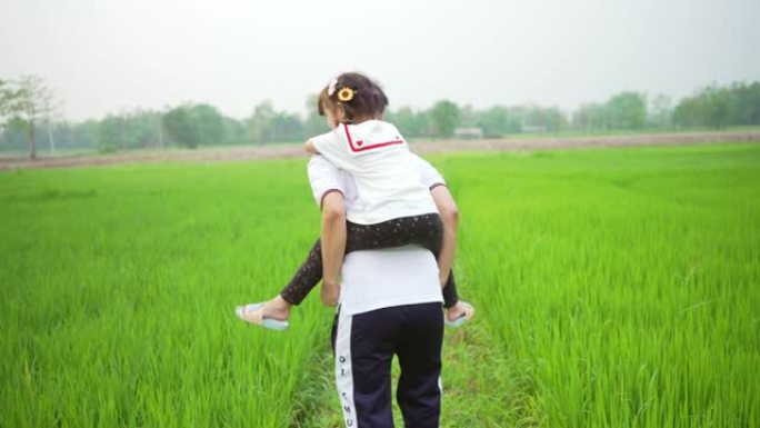 亚洲父女快乐快乐地走在绿色的田野里。