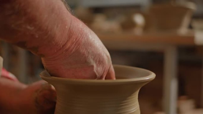 高级男陶工在陶工的轮子上制作花瓶