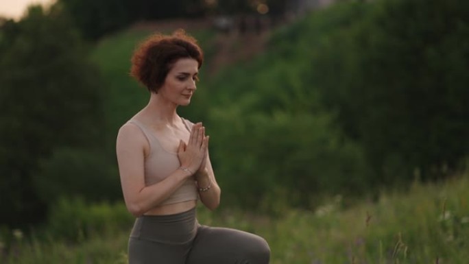 女人在松林日出时练习瑜伽。年轻灵性女孩的剪影在荷花中冥想在户外，慢动作。健身理念，健康生活方式
