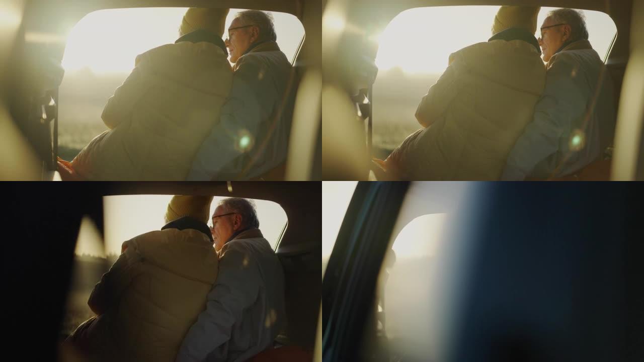 两个老年人在公路旅行中露营。坐在大型汽车后备箱里拥抱