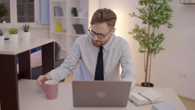 疲惫的公司员工拿着空杯子，在笔记本电脑上工作，精力不足