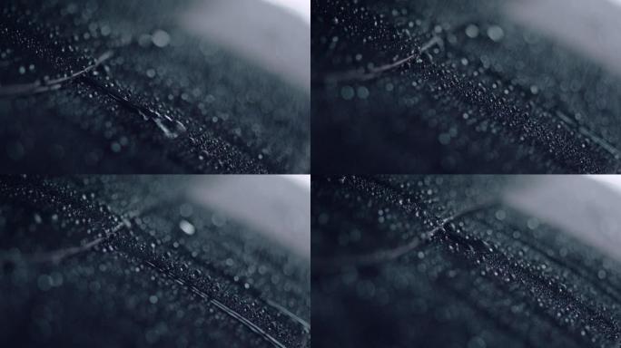 有光泽的深色金属片覆盖着水滴。倾盆大雨。极端特写