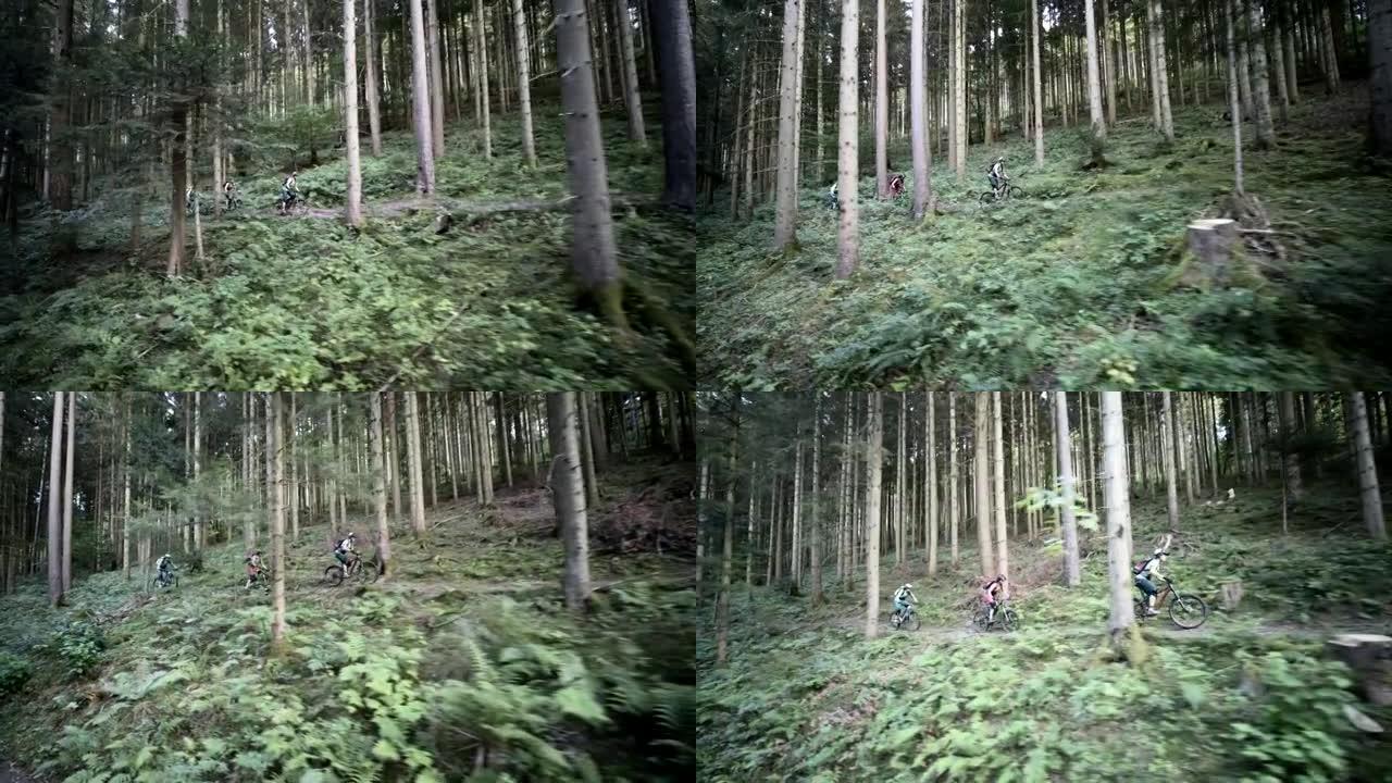 空中无人机拍摄了三个骑在树林中的山地车手