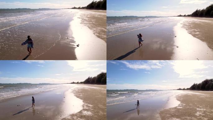 空中拍摄，女人独自行走，晚上在海边用手机拍摄风景照片和自拍照。
