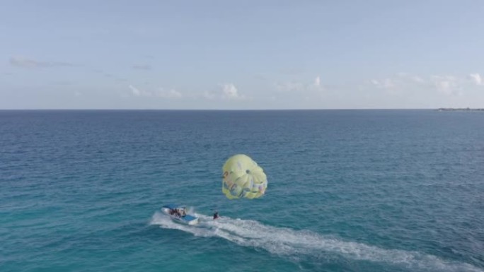 快艇在阳光明媚的日子里在Playa Delfines拉降落伞，鸟瞰图