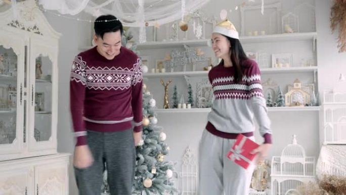 跳舞的亚洲男女爱好者在圣诞节在他家的客厅里送礼物。