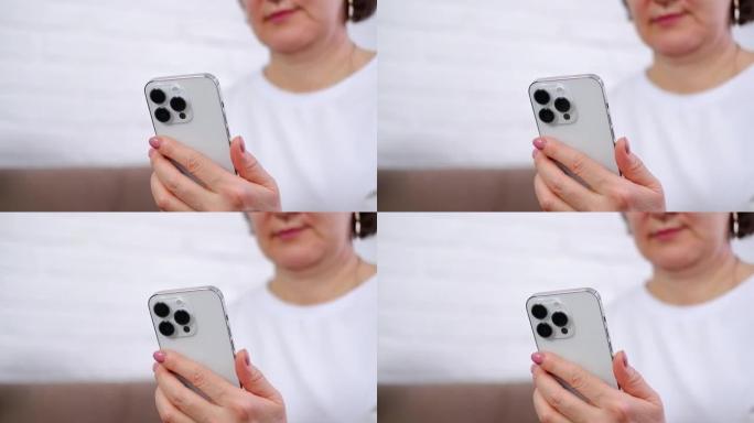 女人的手握着并触摸着iphone 14，在灯光室里看着手机的屏幕。