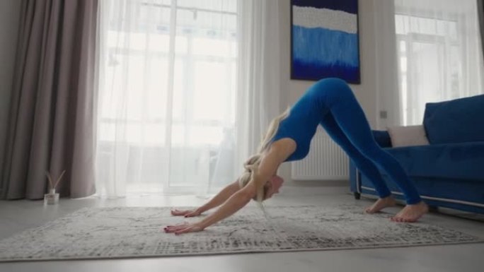 一个女人在家在公寓的地毯上训练。进行家庭练习。在家远程健身伸展和瑜伽。远程培训和健康的生活方式