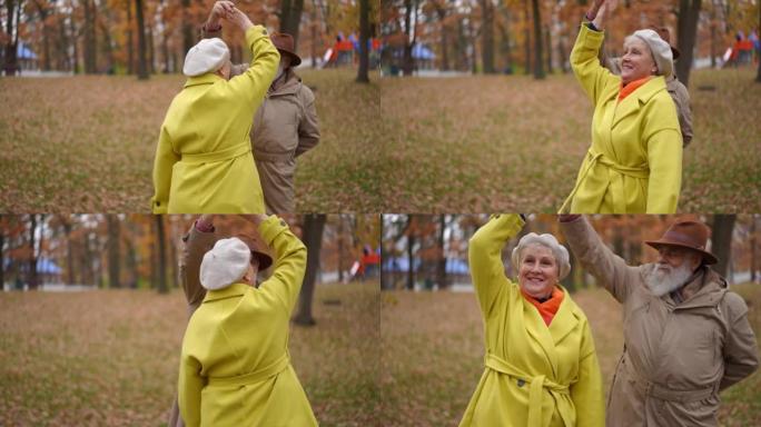 快乐的高级女人在慢动作中旋转，在秋天的公园草地上与爱的男人跳舞。积极自信的白人丈夫和妻子一起享受休闲