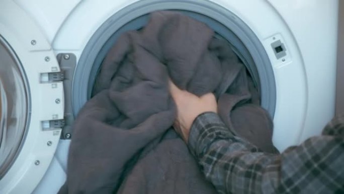 男人的手在家里给洗衣机装上床罩，洗衣服。
