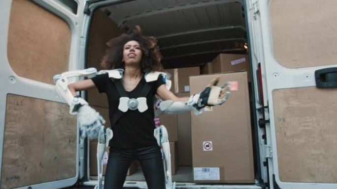电动外骨骼专业女性搬家工人。从卡车上捡起沉重的箱子
