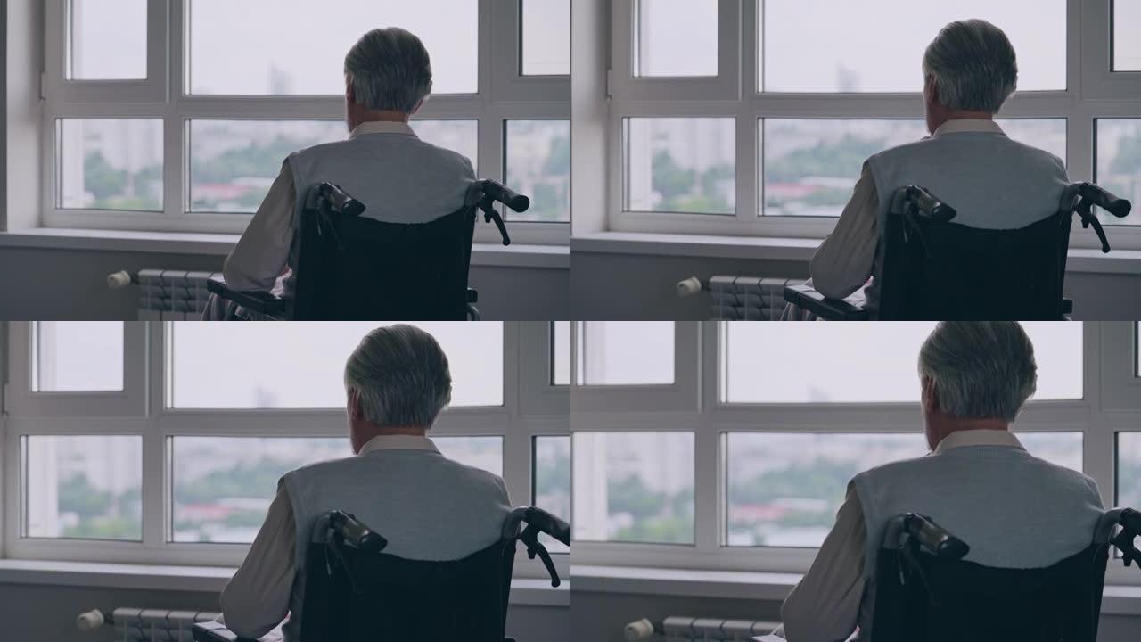 残疾人老人独自坐在轮椅上，透过窗户看