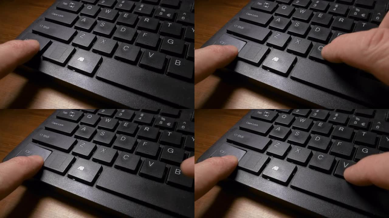 计算机的黑色键盘和男人的手按CTRL和C键进行复制，然后按CTRL和V键进行粘贴命令。特写镜头