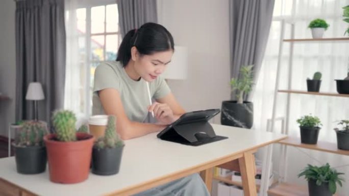 亚洲女性在客厅里玩平板电脑，架子上装饰着植物。